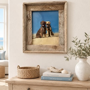 May include: A square picture frame made of weathered, light brown reclaimed wood containing a photograph of a dark brown dog and a golden-colored dog sitting together on a sandy beach against a bright blue sky background.