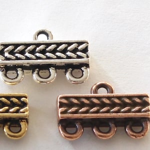 May include: Three rectangular jewelry connectors in silver, gold, and copper tones. Each piece features a central horizontal band with a raised braided pattern and includes one loop on the top edge and three loops along the bottom edge for attachment.