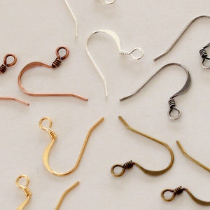 May include: An assortment of earring hooks in various metallic finishes, including copper, silver, gold, and gunmetal. The hooks are displayed against a neutral background, showcasing their different shapes and wire-wrapped details.