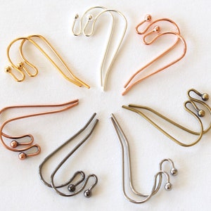 May include: An assortment of metal earring hooks in various colors, including gold, silver, copper, and bronze. Each hook features a unique curved design with decorative ball accents, showcasing a variety of styles for jewelry making.