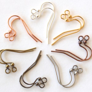 May include: An assortment of earring hooks in various metallic finishes, including copper, gold, silver, and gunmetal. The hooks are arranged in a circular pattern, showcasing their different shapes and styles. The image is taken on a white background.