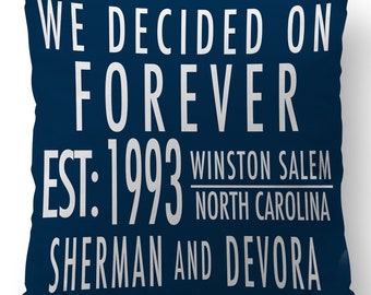 Op de afbeelding: Een donkerblauw kussen met witte tekst die "We decided on forever est. 1993 Winston Salem North Carolina Sherman and Devora" luidt.