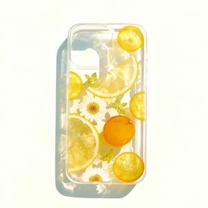 May include: Clear phone case with a design featuring lemon slices, small orange fruit, and white daisy flowers. The case is rectangular with rounded corners and a camera cutout.