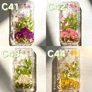 Op de afbeelding: Transparante telefoonhoesjes met geperste bloemen. Elke hoes heeft een andere opstelling van kleurrijke gedroogde bloemen en groene bladeren. De hoesjes zijn gelabeld met C41, C42, C43 en C44.