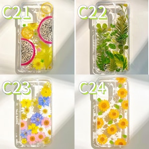 Op de afbeelding: Vier transparante telefoonhoesjes met verschillende ontwerpen. E&eacute;n hoesje heeft drakenfruit en citroenschijfjes. Een ander heeft groene bladeren. Een derde heeft kleurrijke bloemen. De laatste heeft gele zonnebloemen. Elk hoesje heeft een wit label.