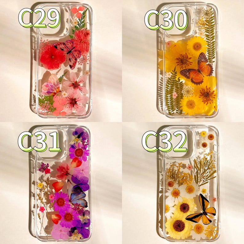 Op de afbeelding: Vier transparante telefoonhoesjes met bloemen- en vlinderontwerpen. Elke hoes heeft een andere opstelling van gedroogde bloemen en een vlinder. De hoesjes zijn gelabeld met C29, C30, C31 en C32.