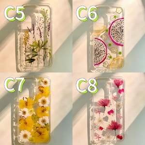 Pode incluir: Quatro capas de telefone transparentes com designs diferentes. Uma capa tem flores secas, outra tem fatias de fruta do drag&atilde;o e lim&atilde;o, uma terceira tem flores amarelas e a &uacute;ltima tem flores e p&eacute;talas cor-de-rosa.