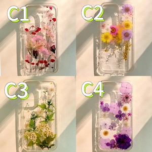 Op de afbeelding: Vier transparante telefoonhoesjes met ingebedde gedroogde bloemen. De hoesjes hebben verschillende bloemstukken: roze en rood, geel en paars, groen en wit en paars en roze. De hoesjes zijn rechthoekig met afgeronde hoeken.