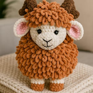 Puede incluir: Un juguete de oveja hecho a mano con ganchillo, con un cuerpo texturizado y esponjoso en tonos naranja y crema. La oveja tiene cuernos marrones, ojos negros y el interior de las orejas rosa. Está sobre una manta crema.