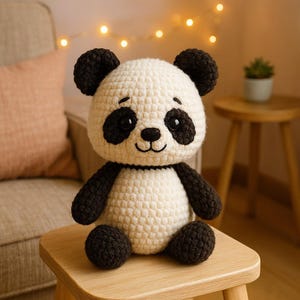 May include: A handmade crochet panda bear with black and white coloring. The panda has black eyes, ears, arms, and legs, with a white body and head. The panda is sitting on a small wooden stool.