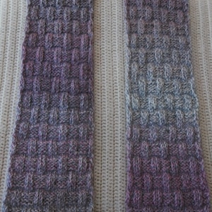 May include: Two knitted scarves in a gradient of purple, gray, and white. The scarves are made with a basket weave stitch.