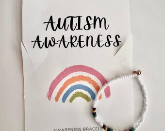 May include: White beaded bracelet with a rainbow of colored beads. The bracelet is on a white card with the text "Autism Awareness" and "Awareness Bracelet".