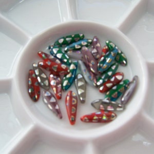 May include: Assortment of colorful glass beads in a variety of shapes and sizes. The beads are arranged in a white plastic tray with multiple compartments.