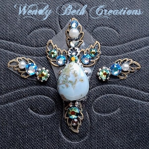 May include: A set of three blue and gold jeweled body stickers with a teardrop-shaped iridescent blue stone in the centre. The stickers are designed to be applied to the body for a decorative look.