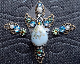 May include: A set of three blue and gold jeweled body stickers with a teardrop-shaped iridescent blue stone in the center. The stickers are designed to be applied to the body for a decorative look.