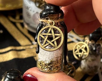 May include: A small glass bottle filled with white salt, dried herbs, and purple crystals. The bottle is topped with a black wax seal and a pentagram charm.