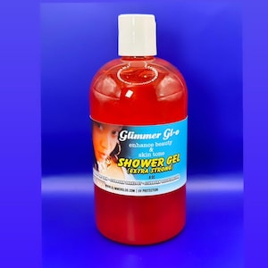 May include: A red plastic bottle of Glimmer Glo shower gel, labeled "enhance beauty & skin tone" and "EXTRA STRONG". The bottle is 8 oz and has a white cap. The label also includes the website www.slimmerglo.com and "UV PROTECTION".