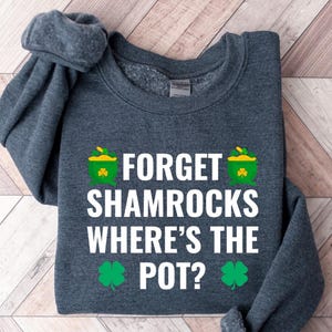 May include: A dark gray sweatshirt with the text "Forget Shamrocks Where's the Pot?" in white. The text is surrounded by green shamrocks and gold pots of gold.