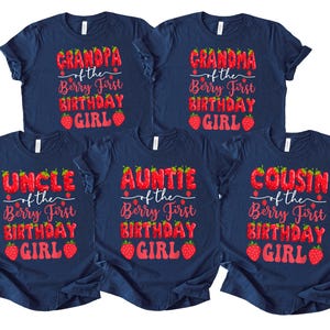May include: Navy blue t-shirts with red text and strawberry graphics. The shirts read "Grandpa," "Grandma," "Uncle," "Auntie," and "Cousin" above "of the Berry First Birthday Girl."