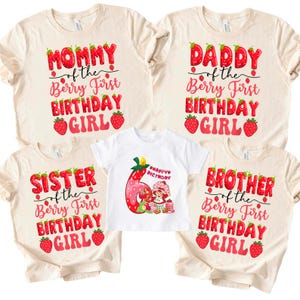 May include: A collection of matching family birthday shirts. The shirts are cream-colored and white, with red and pink text that reads "Mommy", "Daddy", "Sister", and "Brother" with "of the Berry First Birthday Girl". A smaller white shirt has a strawberry graphic.