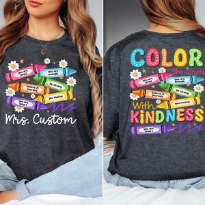 K&ouml;nnte beinhalten: Dunkelgraues T-Shirt mit einem bunten Buntstift-Design. Auf der Vorderseite steht "Mrs. Custom" und Buntstifte mit positiven Botschaften. Auf der R&uuml;ckseite steht "Color the world with kindness."