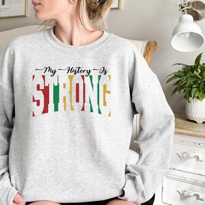 May include: Grey sweatshirt with the text "My History Is Strong" in colourful letters. The letters are outlined in black and have a vintage look.