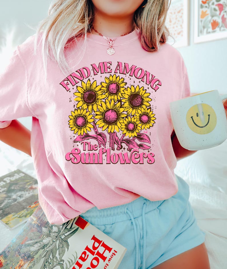 May include: Pink t-shirt with a graphic of sunflowers and the text "Find Me Among The Sunflowers".