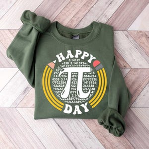 May include: A green sweatshirt with a white graphic design that says "Happy Pi Day" with a large pi symbol surrounded by numbers.