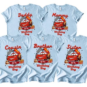 Pu&ograve; includere: Magliette azzurre con una grafica di un'auto da corsa rossa, una bandiera a scacchi e le scritte "Daddy", "Mommy", "Cousin", "Brother" e "Sister" sopra "Of The Birthday Boy".