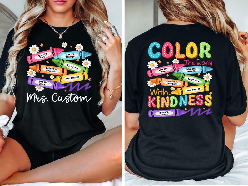 K&ouml;nnte beinhalten: Schwarzes T-Shirt mit einem bunten Buntstift-Design. Die Vorderseite zeigt Buntstifte mit positiven Botschaften und dem Text "Mrs. Custom". Auf der R&uuml;ckseite steht "COLOR the world with KINDNESS."