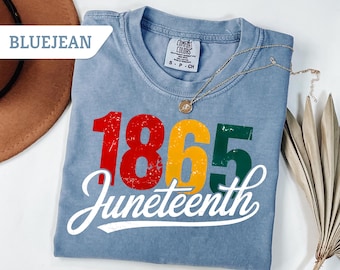May include: A blue t-shirt with the text "1865 Juneteenth" in red, yellow, and green. The text is in a vintage style font.