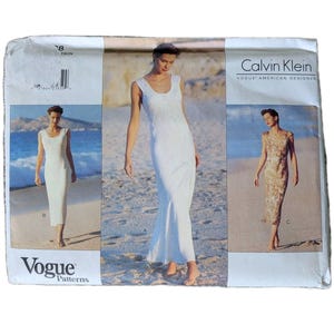 May include: A Calvin Klein Vogue American Designer sewing pattern envelope featuring three variations of a sleeveless, scoop-neck dress. The images show a solid white floor-length dress, a mid-calf white dress, and a patterned mid-calf dress.