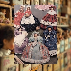 May include: A selection of handmade fabric dolls, each wearing a distinctive dress and bonnet. The dolls display intricate stitching and lace detailing, with diverse patterns and colours, such as red, blue, and purple. The dolls are presented together, highlighting their individual designs.