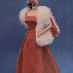 May include: A vintage doll in a red strapless gown and a white faux fur stole. The doll has blonde hair in an updo and a pearl necklace. The background is a solid blue.