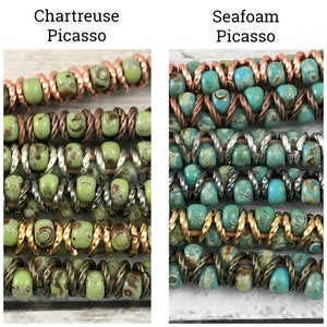 May include: Close-up of two strands of multi-colored beads. The beads are green and brown with white flecks, and turquoise and brown with white flecks. The beads are arranged in a pattern of alternating colors. The text "Chartreuse Picasso" and "Seafoam Picasso" is above each strand of beads.
