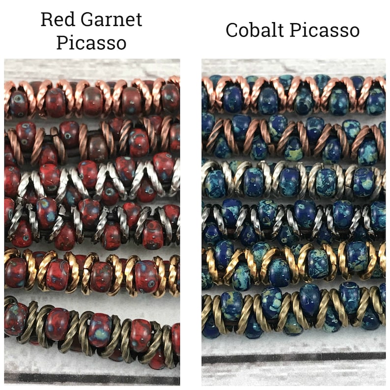 May include: Two strands of multi-colored beads, one red and one blue, with copper, silver, and gold accents. The red strand is labeled "Red Garnet Picasso" and the blue strand is labeled "Cobalt Picasso".