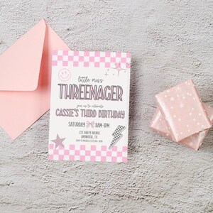 Puede incluir: Una invitaci&oacute;n de cumplea&ntilde;os rosa con un patr&oacute;n de cuadros y el texto "little miss THREENAGER" se muestra. La invitaci&oacute;n incluye detalles para el tercer cumplea&ntilde;os de Cassie. Tambi&eacute;n se ven un sobre rosa y dos regalos envueltos.
