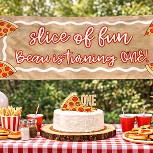 May include: A festive outdoor party scene with a banner reading "slice of fun, Beau is turning ONE!" Pizza-themed decorations include a cake, pizza slices, and a red and white checkered tablecloth. Balloons and food complete the birthday celebration.