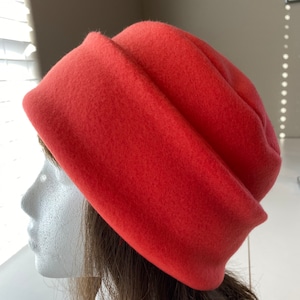 May include: A bright orange felt beret hat. The hat is folded over at the brim and has a soft, fuzzy texture.