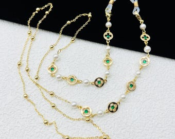 May include: Two gold chains with green and white accents. The chains have small round beads and decorative charms with green gemstones. The chains have clear silicone loops at the ends.