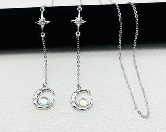 May include: Two silver necklaces with a crescent moon pendant and a star charm. The moon pendant has an iridescent stone in the center.