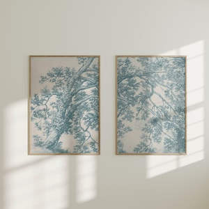 May include: Two framed art prints featuring a blue and white tree design. The artwork has a vintage aesthetic, with the tree branches and leaves rendered in a detailed, illustrative style. The frames are a light brown color, adding to the classic look.