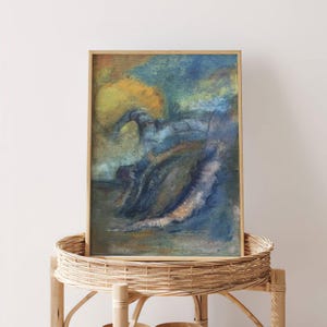 May include: Abstract art print in a wooden frame. The artwork features a blend of blues, greens, and yellows, with brushstrokes creating a textured appearance. The framed art is displayed on a natural woven basket stand.