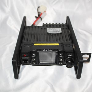 May include: A black AnyTone mobile radio transceiver mounted in a black metal bracket. The front panel features a central display screen, a power button, six programmable buttons labeled P1 through P6, a function button, and a rotary dial.