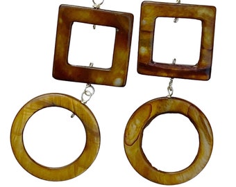 May include: A pair of brown and gold geometric earrings with a square and circle design. The earrings are made of a natural material with a marbled pattern.