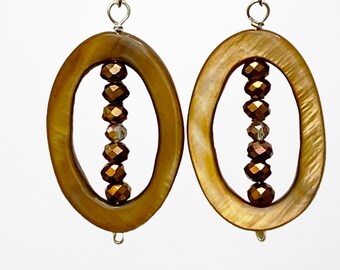 May include: A pair of oval-shaped earrings with a brown shell-like material and a silver hook. Each earring has a vertical line of brown and clear faceted beads.