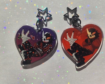 May include: Two heart-shaped acrylic charms. One is purple with a white and black character design, the other is red with a similar character. Both have a star-shaped clasp. The charms feature the text "GIRLS WEAR".
