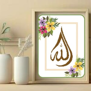 Op de afbeelding: Een ingelijst kunstwerk met het Arabische woord voor God, "Allah", in bruin tegen een witte achtergrond. Het kunstwerk is versierd met bloemaccenten in paars, geel en roze en is geplaatst in een licht houten frame.