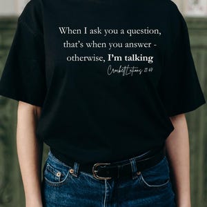 May include: Black t-shirt with white text that reads "When I ask you a question, that's when you answer - otherwise, I'm talking Crockett Lations 21:47".