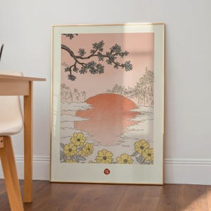 Puede incluir: Una impresi&oacute;n enmarcada de un paisaje de inspiraci&oacute;n japonesa con un gran sol naranja poni&eacute;ndose detr&aacute;s de una l&iacute;nea de &aacute;rboles y una rama de delicadas flores blancas. La impresi&oacute;n tiene un fondo rosa claro y un borde de flores amarillas. La palabra "福" est&aacute; impresa en rojo en la parte inferior de la impresi&oacute;n.
